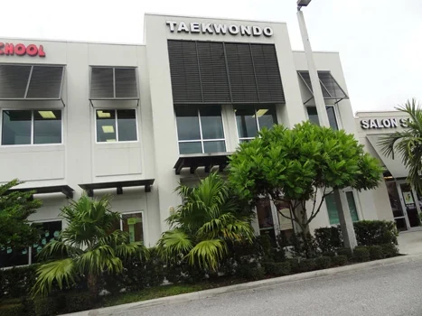 Taekwondo studio storefront with tall windows and landscaped planting beds