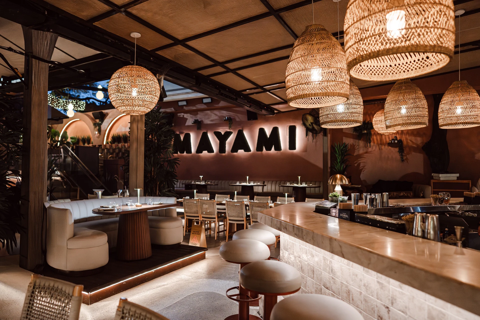 Mayami Wynwood dining room with woven pendant lights, wood ceiling details, and a curved bar