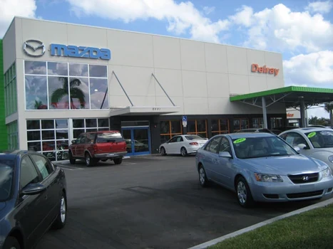 Mazda dealership showroom entrance with vehicles parked outside
