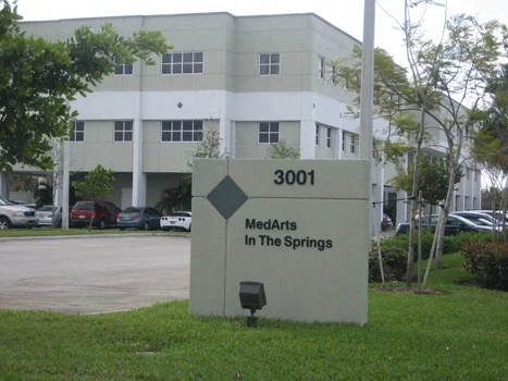 Medical office building behind a landscaped lawn and entrance sign