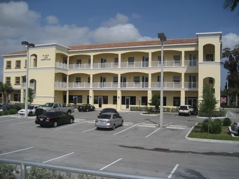 Three-story mixed-use building with long balconies and parking in front