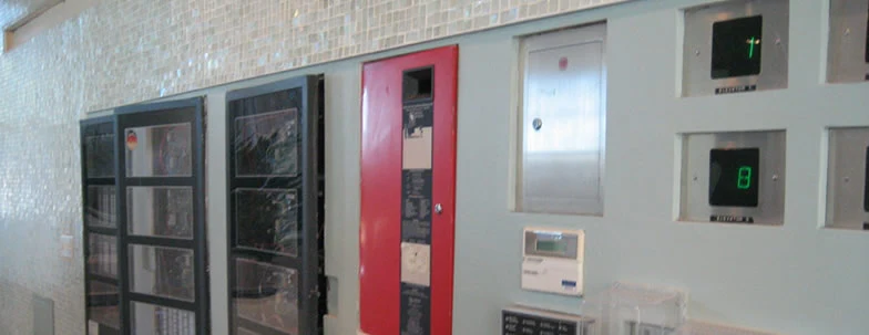 A bank of wall-mounted fire alarm and building control panels