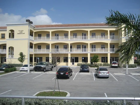 Plaza Las Americas building with balconies and a parking area in front