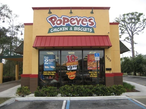 Popeyes restaurant entrance with a red awning and yellow facade
