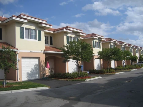 Row of two-story townhouses with tile roofs and landscaped front entrances