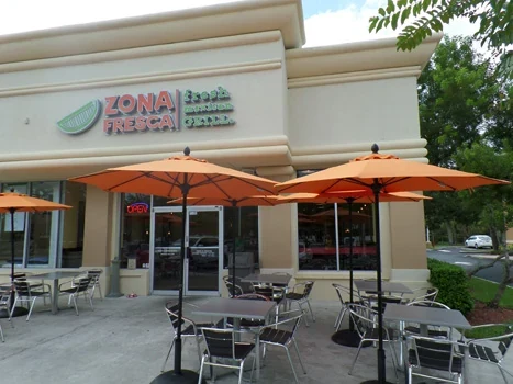 Zona Fresca storefront with orange umbrellas over outdoor tables